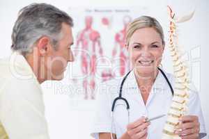 Smiling doctor showing her patient a spine model