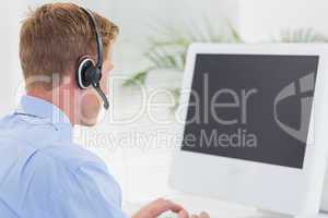 Handsome agent with headset typing on keyboard