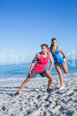 Happy couple stretching together beside the water