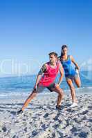 Happy couple stretching together beside the water