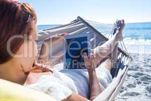 Brunette using tablet while relaxing in the hammock