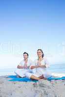 Happy couple doing yoga beside the water