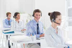 Business team working on computers and wearing headsets