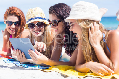 Happy friends wearing sun glasses and using tablet