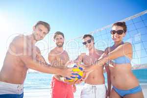 Group of friends holding volleyball and smiling at camera