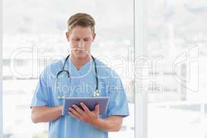 Doctor writing on clipboard beside windows