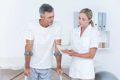 Doctor showing clipboard to her patient with crutch