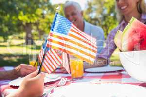 Happy family having picnic and holding american flag