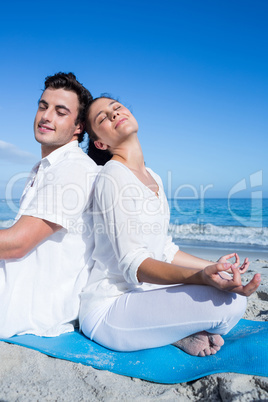 Happy couple doing yoga beside the water