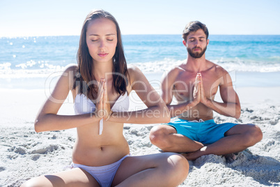 Happy couple doing yoga beside the water