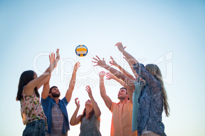 Happy friends throwing volleyball