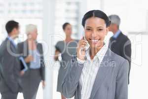 Businesswoman using mobile phone with colleagues behind