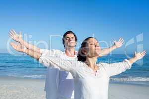 Happy couple doing yoga beside the water