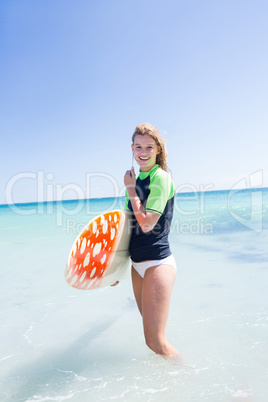 Fit blonde woman standing in the water and holding surfboard