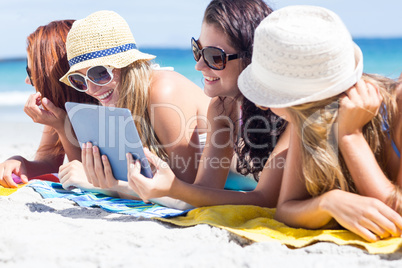 Happy friends wearing sun glasses and using tablet