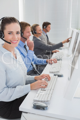 Business team working on computers and wearing headsets