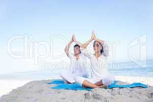 Happy couple doing yoga beside the water