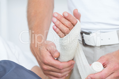 Doctor bandaging his patient hand