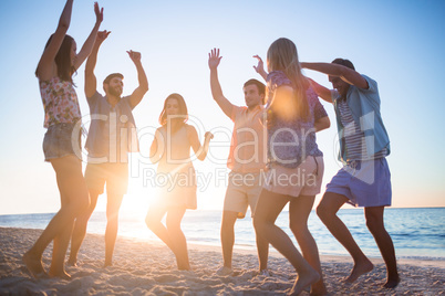 Happy friends dancing on the sand