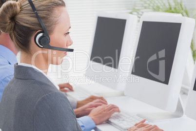 Business team working on computers and wearing headsets