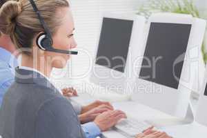 Business team working on computers and wearing headsets