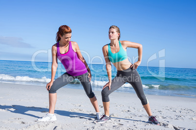 Friends stretching together beside the water