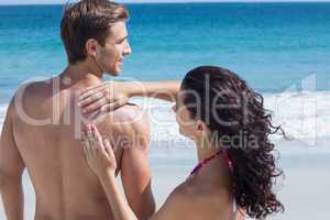 Pretty brunette putting sun tan lotion on her boyfriend