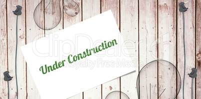 Under construction against wooden background with plugs
