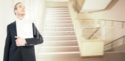 Composite image of businessman looking up holding laptop