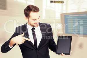 Composite image of happy businessman pointing with his tablet