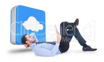 Composite image of businessman lying on floor using tablet