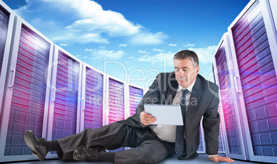 Composite image of mature businessman sitting using tablet