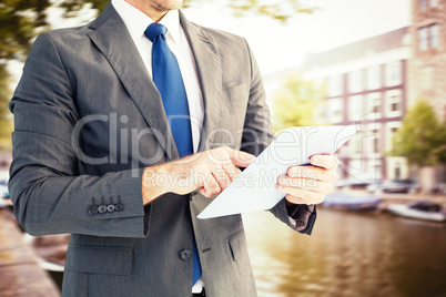 Composite image of businessman using his tablet pc