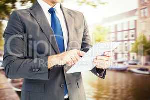 Composite image of businessman using his tablet pc