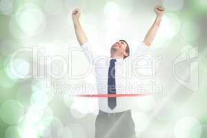 Composite image of businessman celebrating success with arms up