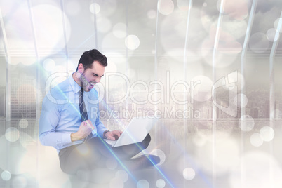 Composite image of cheering businessman sitting using his laptop