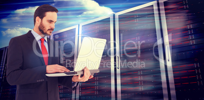 Composite image of focused businessman using his laptop