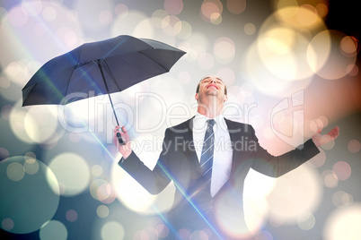 Composite image of businessman sheltering under black umbrella t