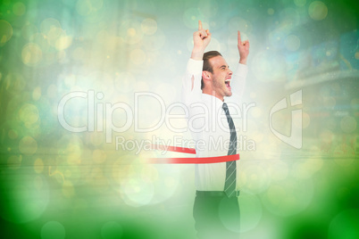Composite image of happy businessman crossing the finish line an