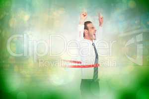 Composite image of happy businessman crossing the finish line an