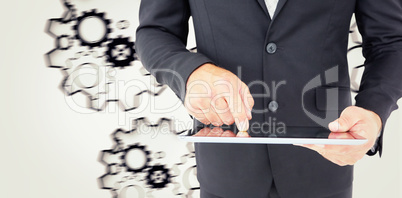 Composite image of businessman using his tablet pc