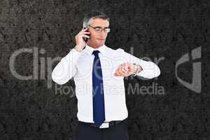 Composite image of businessman on the phone looking at his wrist