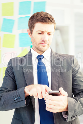 Composite image of businessman sending a text message