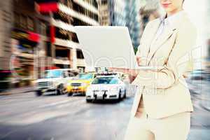 Composite image of confident businesswoman holding laptop