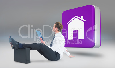 Composite image of businessman using tablet with feet up on brie