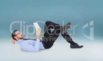 Composite image of businessman lying on the floor while reading