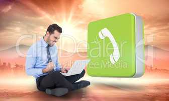 Composite image of cheering businessman sitting using his laptop
