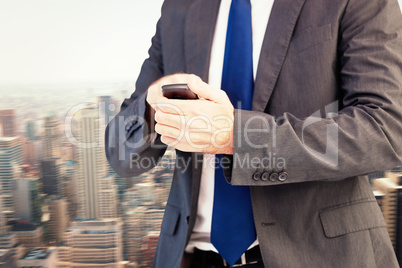 Composite image of focused businessman texting on his mobile pho