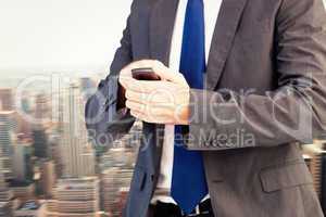 Composite image of focused businessman texting on his mobile pho