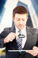 Composite image of businessman looking at tablet with magnifying